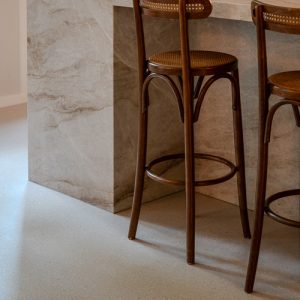 Close-up van barkrukken op de Zilva Barosso gietvloer met marmerkorrels naast een marmeren keukenblok.