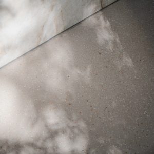 Close-up van Zilva Barosso gietvloer met marmerkorrels en marmeren keukenblok.