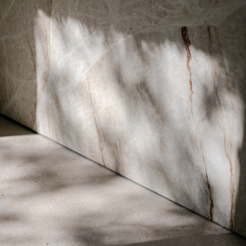 Close-up van Zilva Barosso gietvloer met marmerkorrels in keuken met schaduwspel Close-up van Zilva Barosso gietvloer met marmerkorrels en marmeren keukenblok.